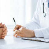 patient and doctor taking notes close up of patient and doctor taking notes